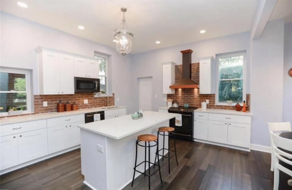 White kitchen with island and copper hood.