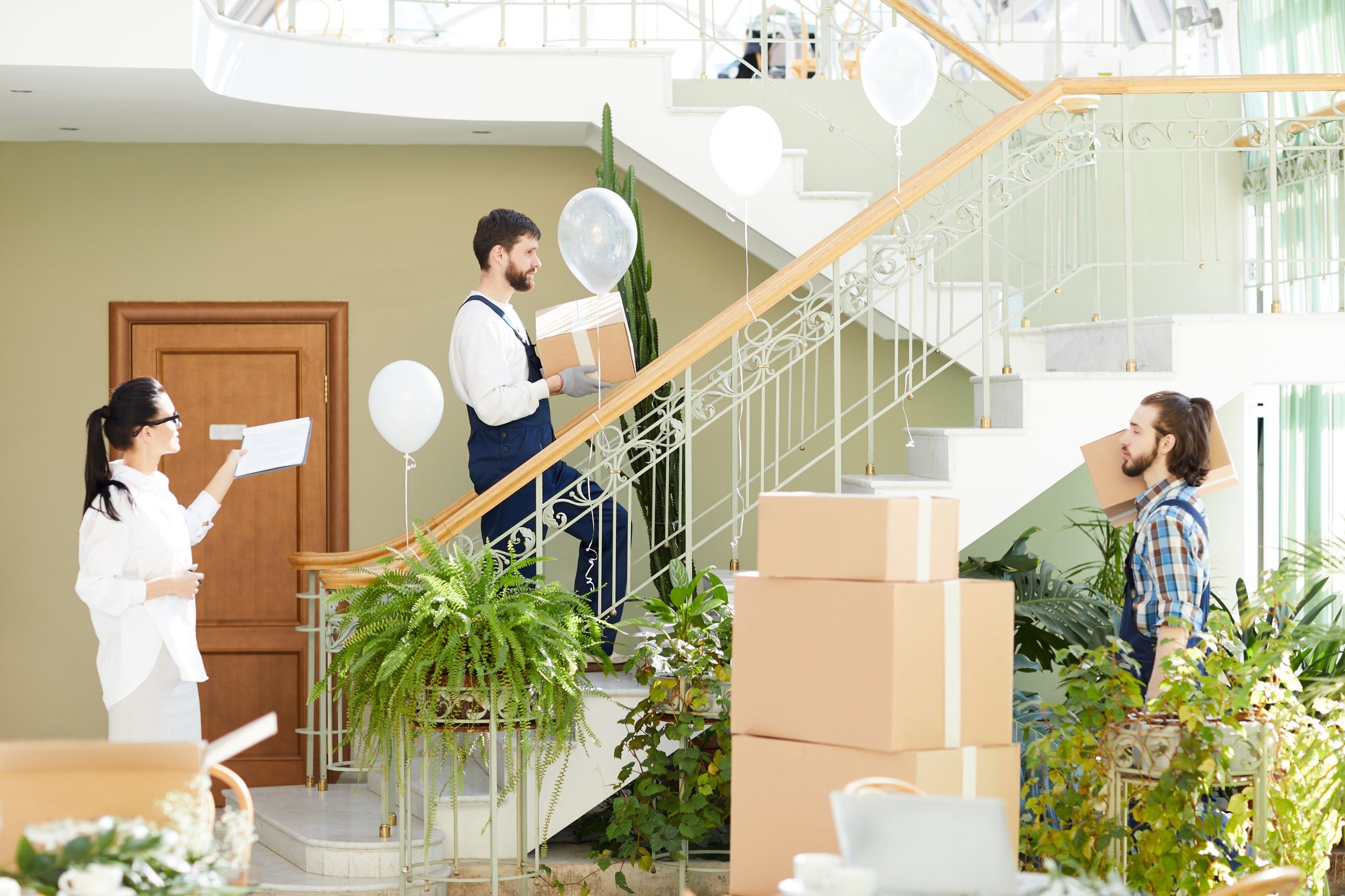 People moving boxes in a bright space.